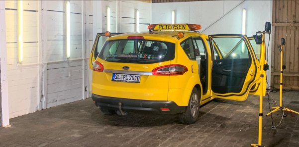 Fahrzeug steht zur Begutachtung mit geöffneten Türen im Arbeitsbereich, mobile Stativbeleuchtung daneben
